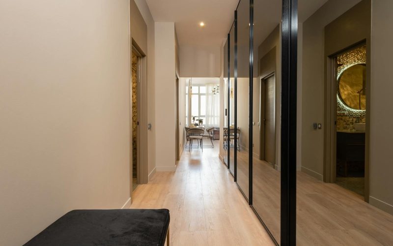 Elegant hallway in a modern apartment featuring large mirrors and natural light.