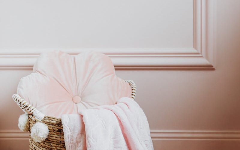 Elegant wicker basket with a plush pink blanket and cushion, perfect for home decor inspiration.