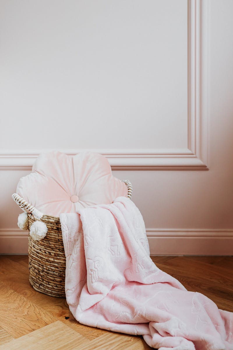 Elegant wicker basket with a plush pink blanket and cushion, perfect for home decor inspiration.