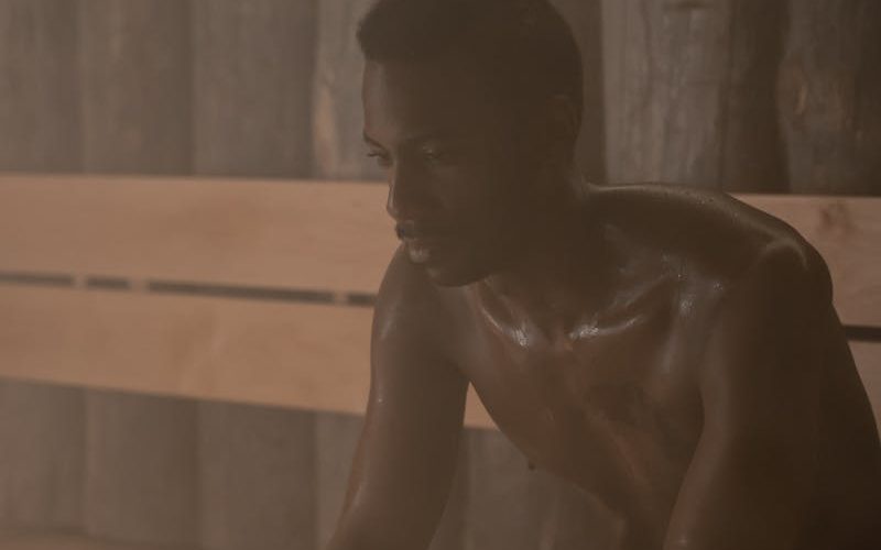 A man enjoying relaxation and selfcare in a dimly lit sauna setting, embracing wellness and tranquility.