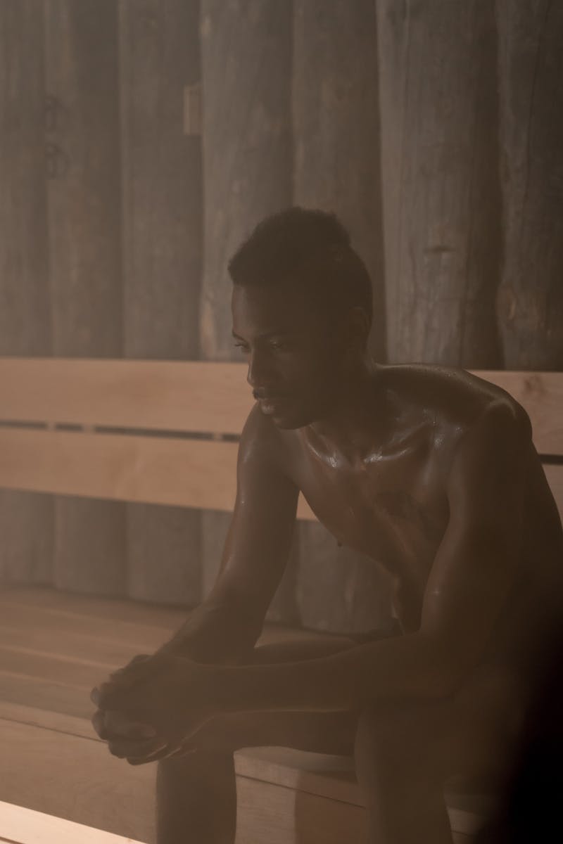 A man enjoying relaxation and selfcare in a dimly lit sauna setting, embracing wellness and tranquility.