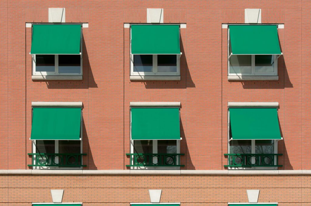 Exterior view of a brick apartment building with green awnings.