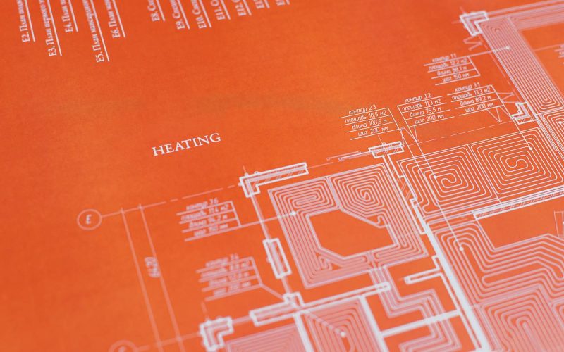Close-up of an orange architectural heating blueprint showing intricate design details.