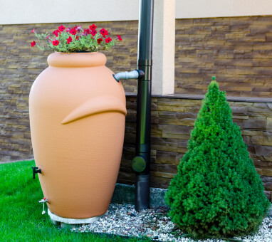 Big,,Flowerpot,Shaped,Rainwater,Tank,With,Flowers,On,Top,,Surrounded